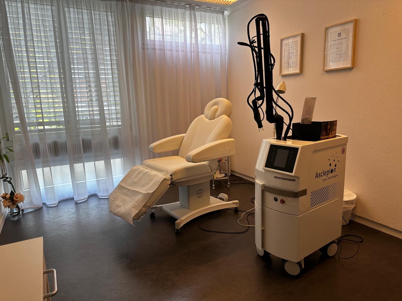 Treatment room with Asclepion laser and diplomas on the wall